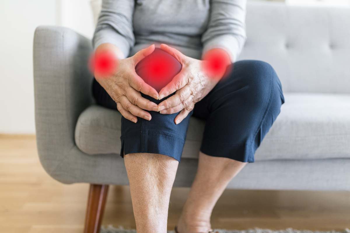 Mature woman experiencing cold weather joint pain in her knees and wrists