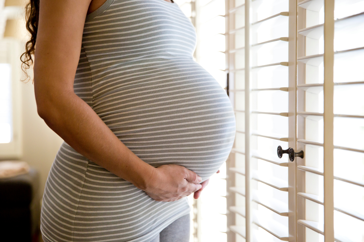 Woman supporting large pregnant belly with hands