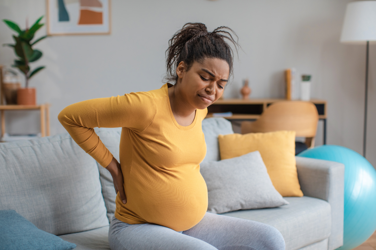 Young pregnant woman experiencing back pain while sitting