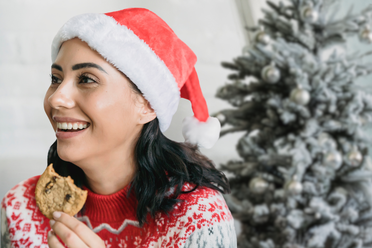 Woman wearing Christmas hat enjoying cookie