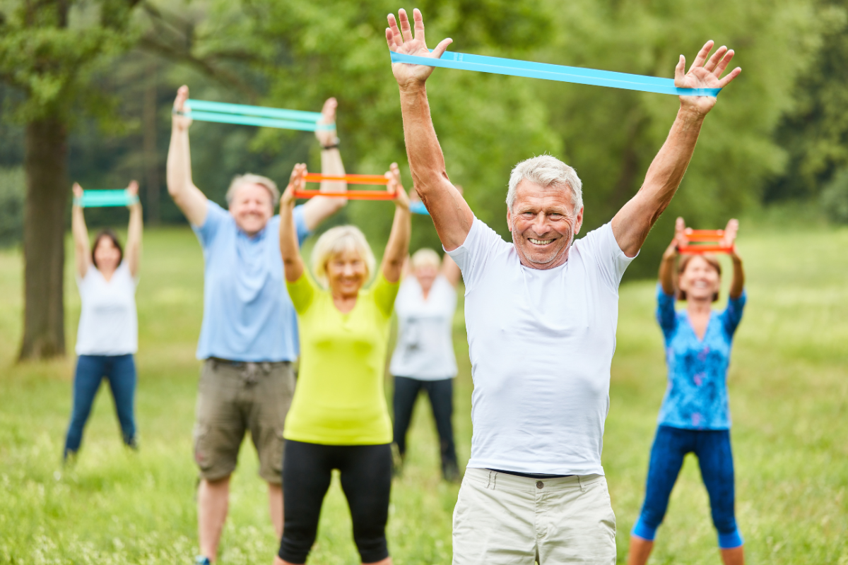 Group of older adults exercising outside with resistance bands