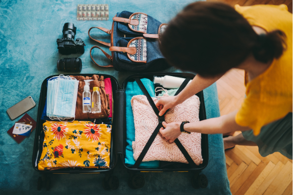 Woman knows how to stay healthy when traveling by packing health essentials in suitcase