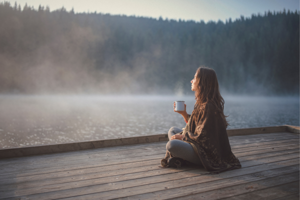 Stress relief methods include being in nature and meditation, as this woman sits on a dock looking at the scenery
