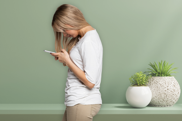 Woman looking down at her phone, exhibiting poor neck posture that can lead to TMJ