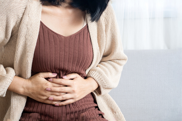Image of a person holding their stomach and experience women's gut health issues
