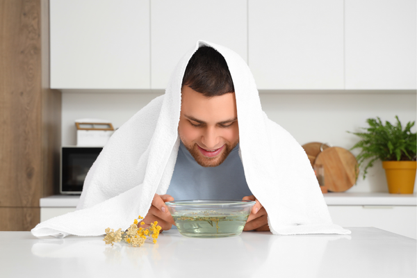Man showing natural flu treatment by breathing in steam in kitchen