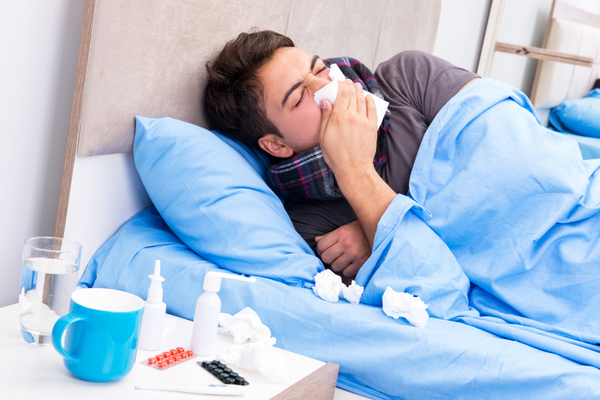 Sick man in bed who could have prevented the flu if he'd asked how does the flu spread