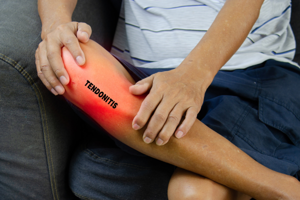 An image of a man holding his knee due to tendonitis