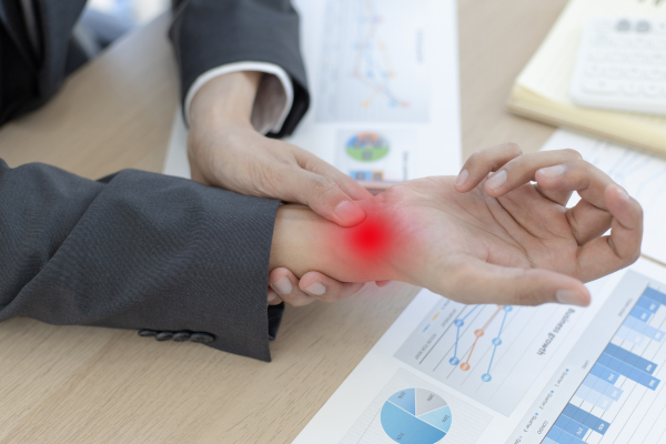 Person experiencing wrist pain from repetitive strain injuries due to desk work