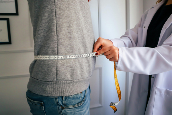 A healthcare provider measuring a man's waist
