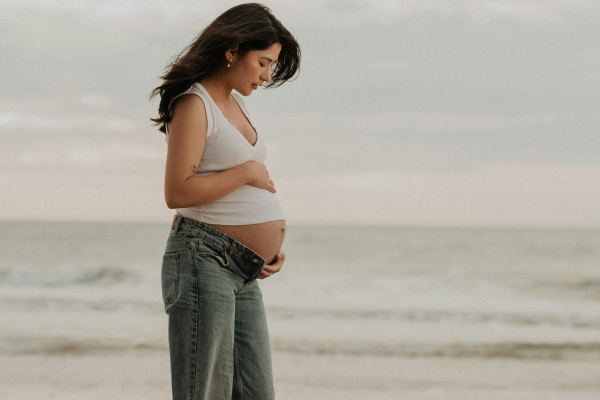 A young woman holding and supporting her pregnant belly
